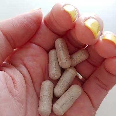 A handful of Vita Boost Max Sleep Support capsules shown in a customer's hand, highlighting the natural herbal supplement.