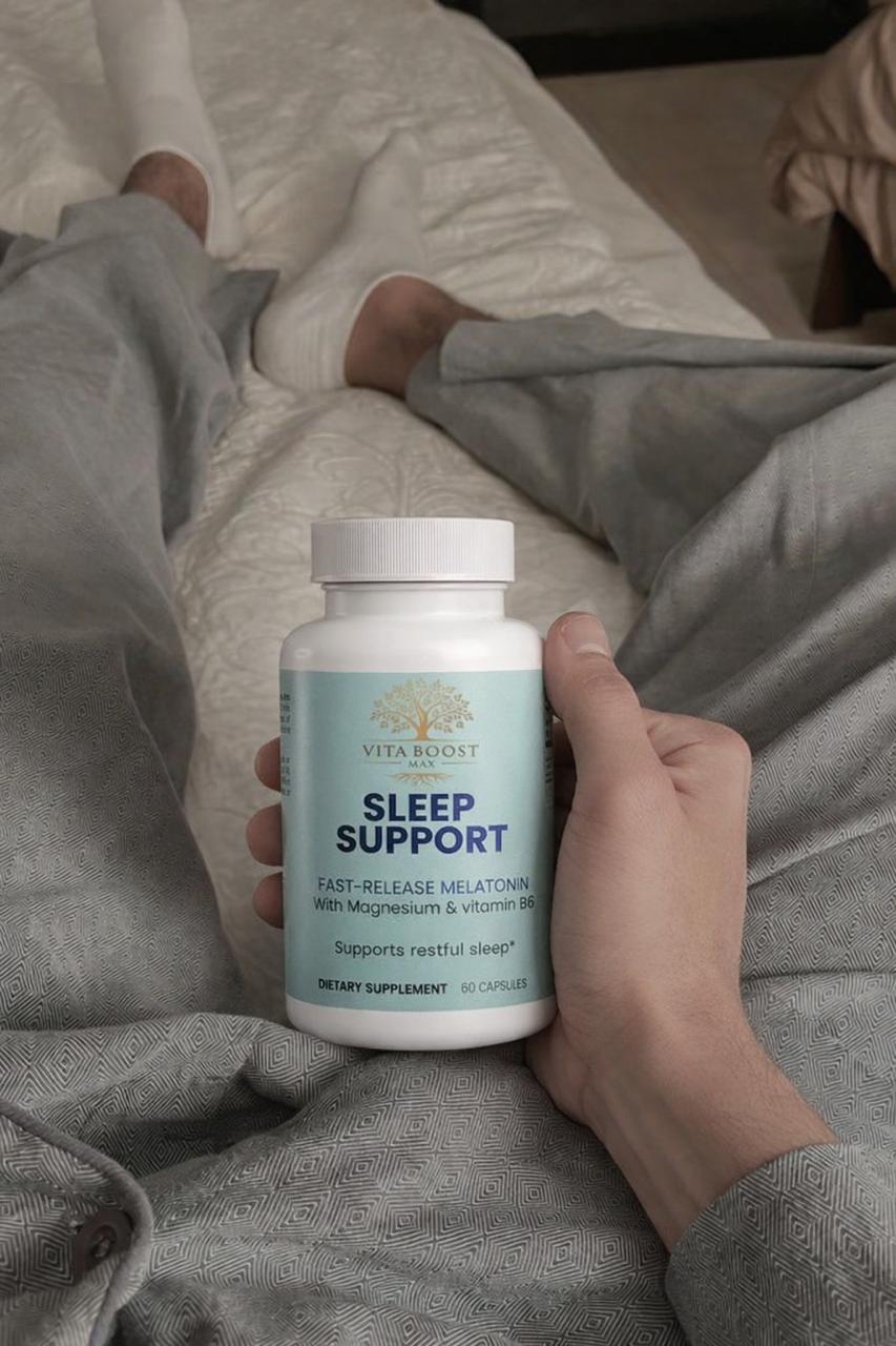 A customer holding a bottle of Vita Boost Max Sleep Support while relaxing in bed, showing how they use this natural melatonin and magnesium supplement for a better bedtime routine.